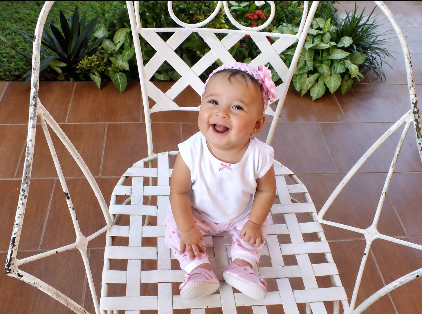 Valery bebé sentada y sonriendo en una silla blanca